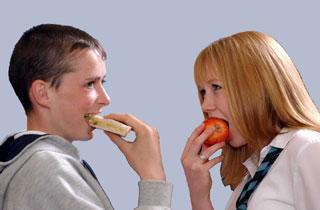 Boy and girl eating sandwich and apple